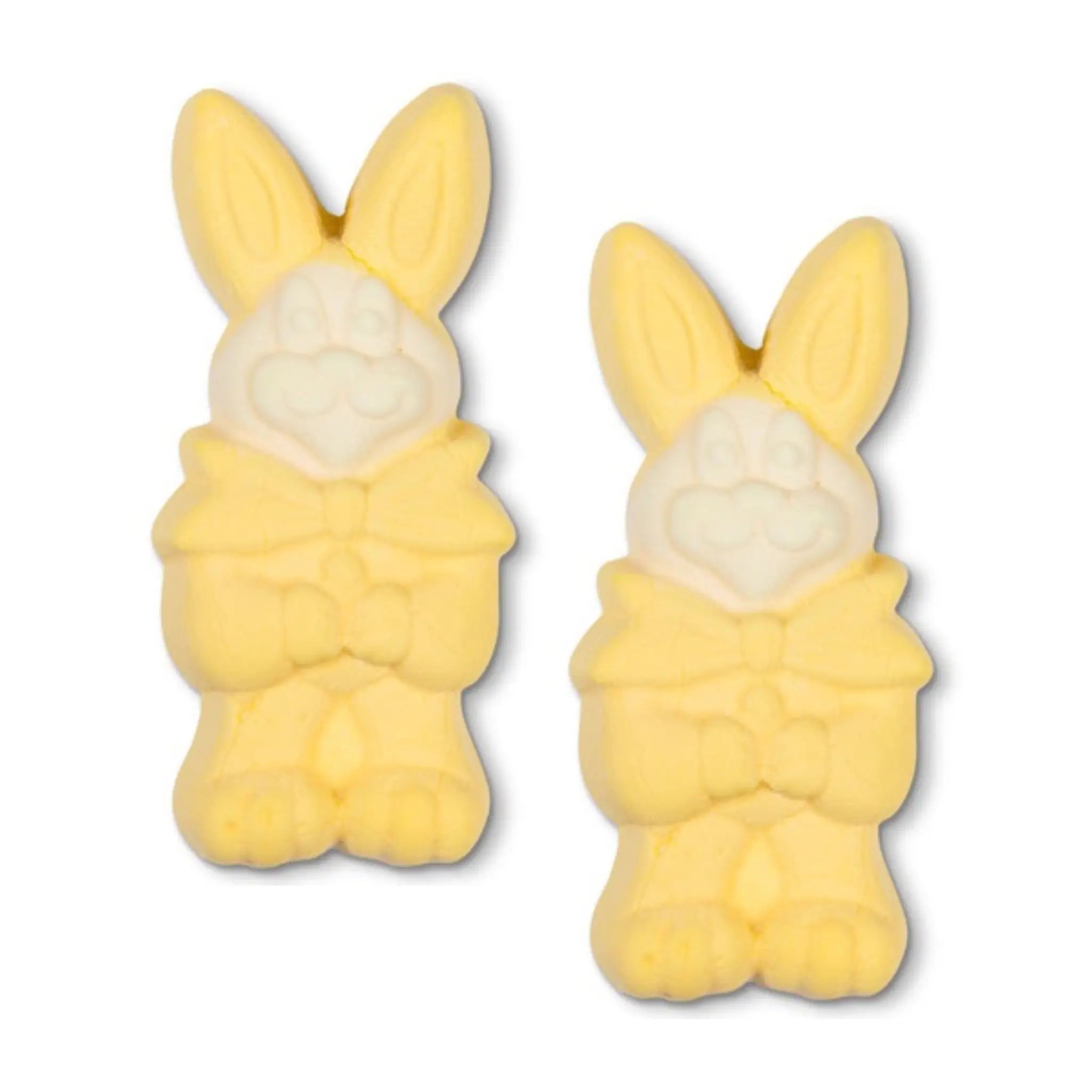 Two Swedish candy pieces in the shape of Easter bunnies in yellow with white faces.