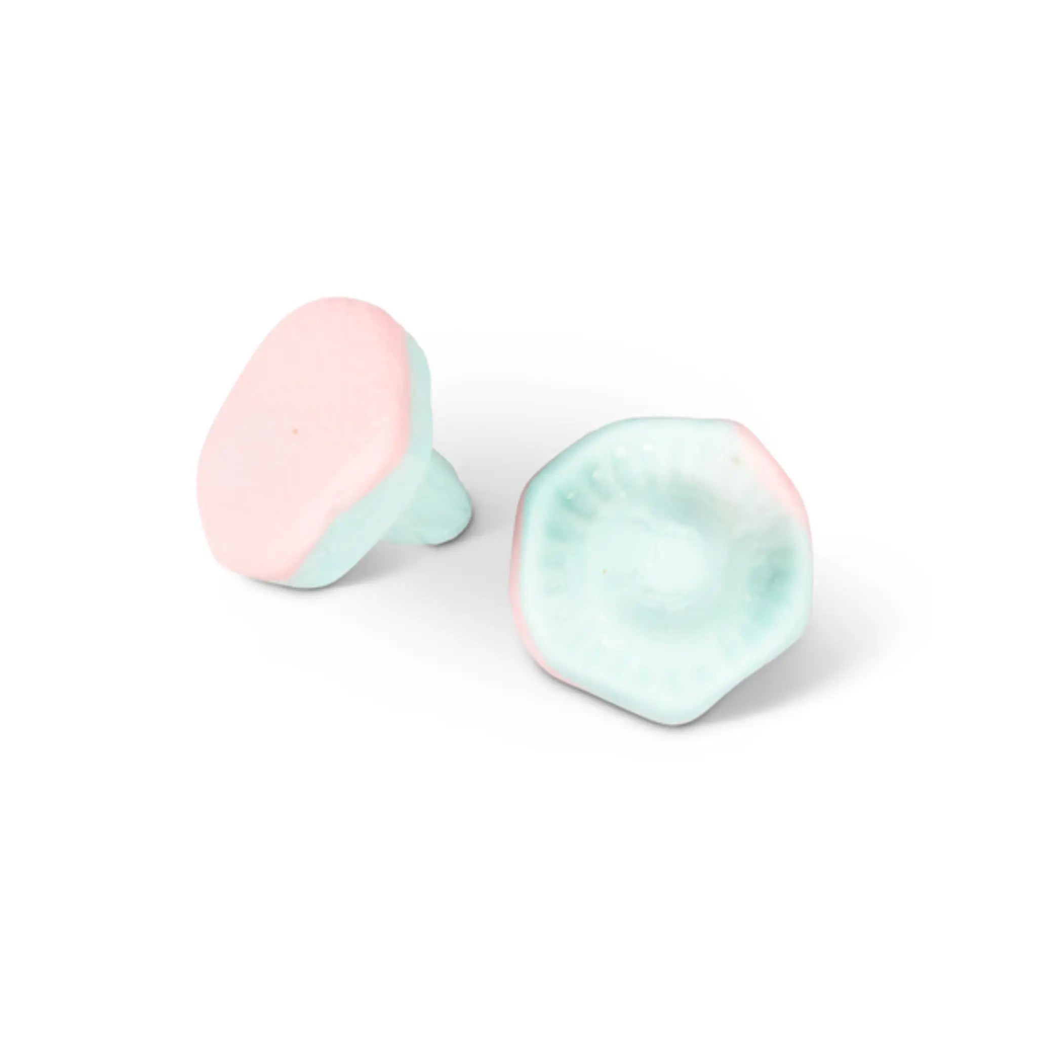 Two pieces of Swedish candy in the shape of mushrooms, in light blue and pink.