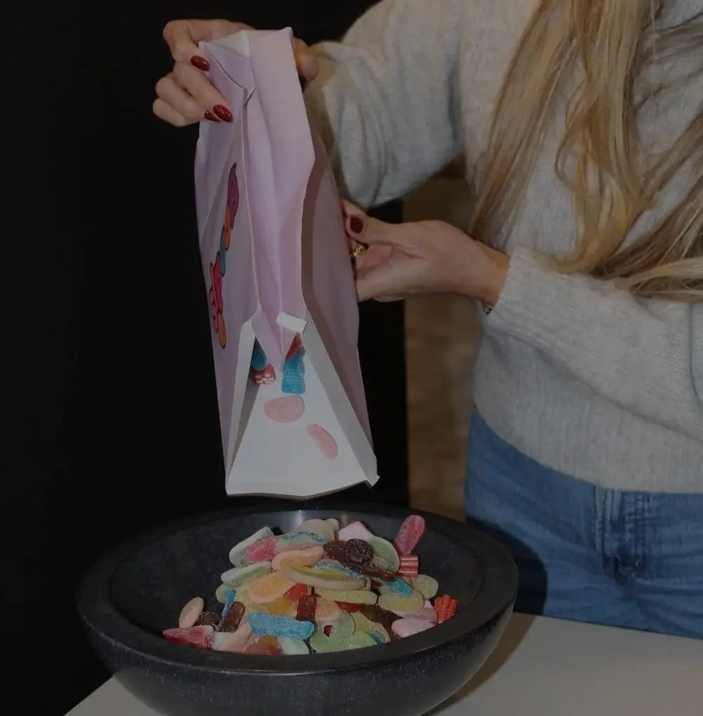 Woman filling a bowl of candy from a bag.