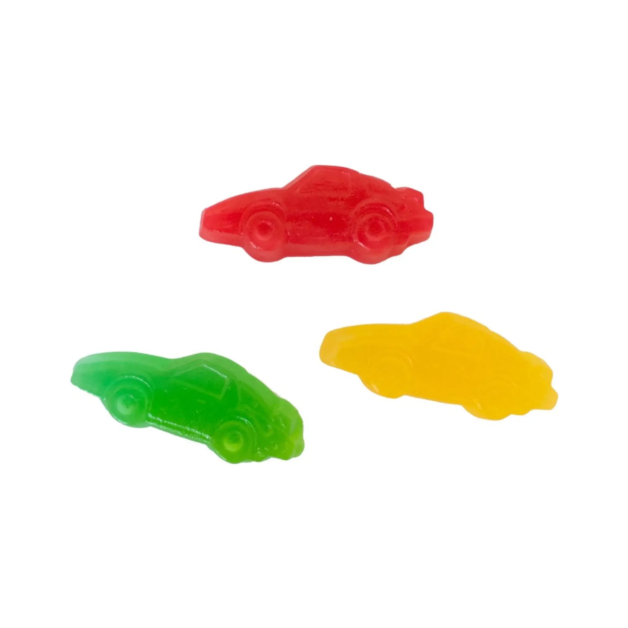 Three pieces of Swedish candy in the shape of cars, in green, yellow and red.