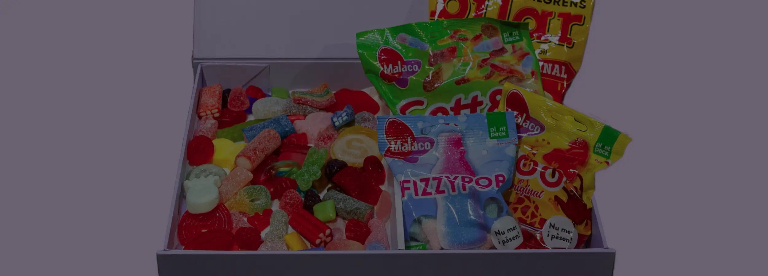 An open gift box of Swedish candy in different shapes and pieces and also in bags.