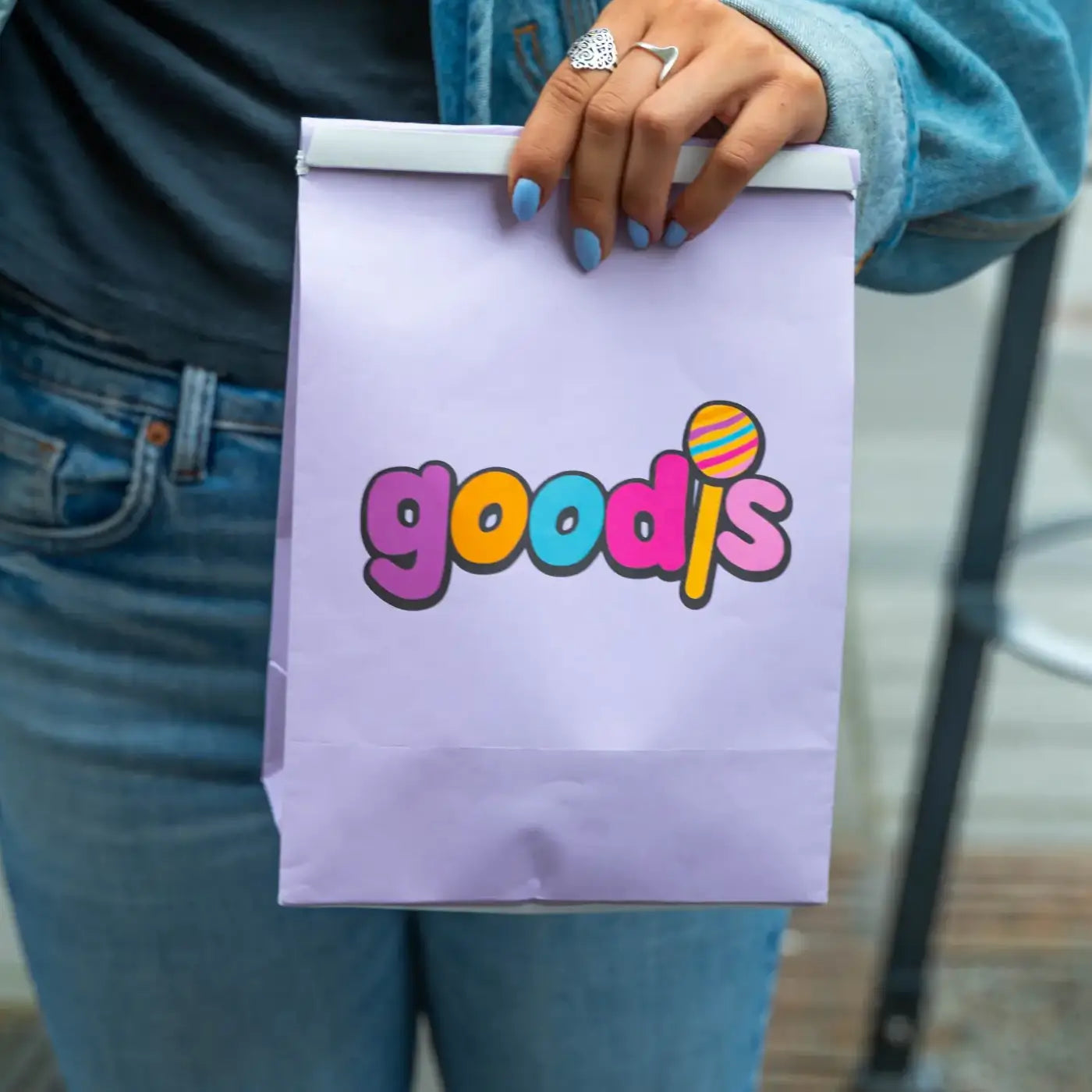 Woman holding a purple bag of Swedish candy with the logo "Goodis" on it.
