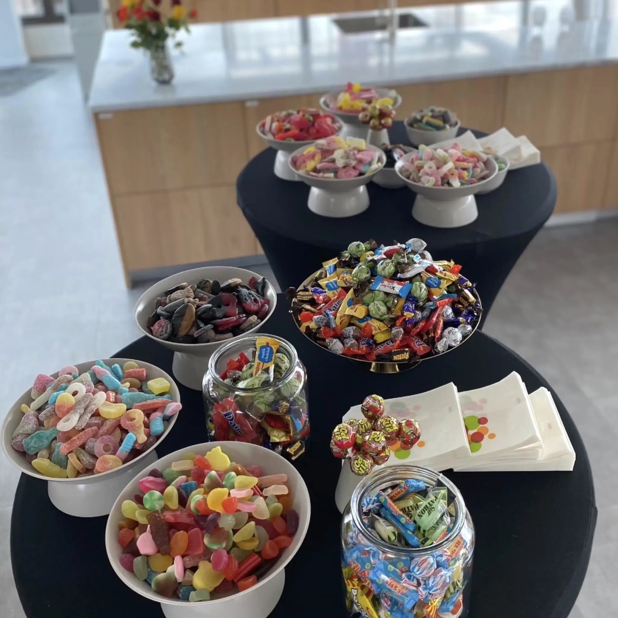 Different kinds of Swedish candy in bowls on two tables in a kitchen.